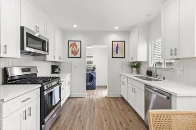 a kitchen with white cabinets and a stove top oven at The Stylish Cozy Bungalow in North Park in San Diego