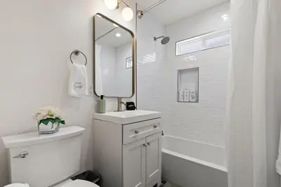 a white bathroom with a sink and a mirror at The Stylish Cozy Bungalow in North Park in San Diego