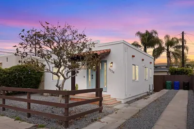 a white house with a fence in front of it at The Stylish Cozy Bungalow in North Park in San Diego