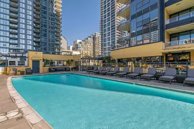 a large swimming pool with lounge chairs and buildings at Little Italy Marina Condo by the Ocean in San Diego