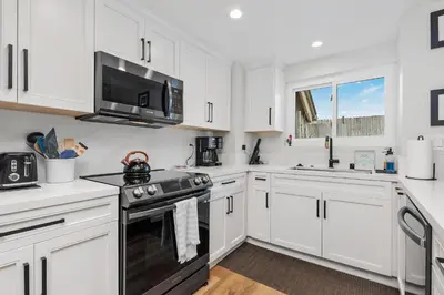 a kitchen with white cabinets and a stove and a microwave at Breeze & Bridle - TC530J in Solana Beach