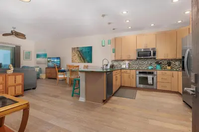 a large kitchen with wooden cabinets and a living room at Coastal Heights - DMBC857C in Solana Beach