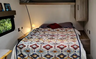 a bed in a small room with a quilt on it at The Owl House in Spring Valley
