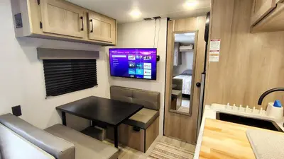 a small kitchen with a table and a tv in a caravan at The Owl House in Spring Valley