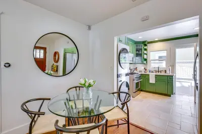 a dining room with green cabinets and a glass table at Walkable Cottage Near Balboa Park with Yard and Grill! in San Diego