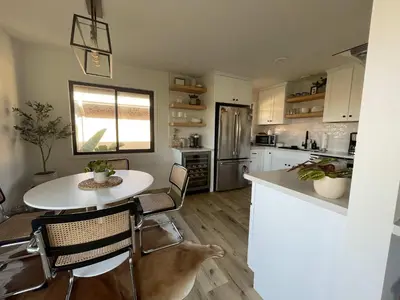 a kitchen with a white table and chairs and a table and a counter at beachside condo in the heart of Bird Rock La Jolla in San Diego
