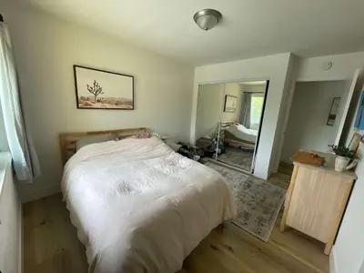 a bedroom with a large white bed and a mirror at beachside condo in the heart of Bird Rock La Jolla in San Diego