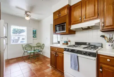 a kitchen with wooden cabinets and a white stove top oven at Spring break 2 blocks to beach pier Newport Ave in San Diego