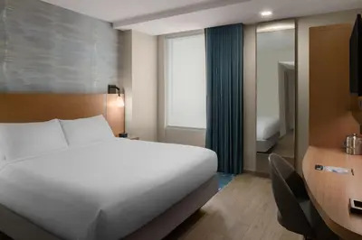 a bedroom with a white bed and a desk and a table at Courtyard by Marriott San Diego Gaslamp/Convention Center in San Diego