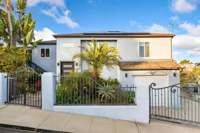 a white house with a gate and trees at Luxurious Pool & Sauna Home with Beautiful Gardens in San Diego