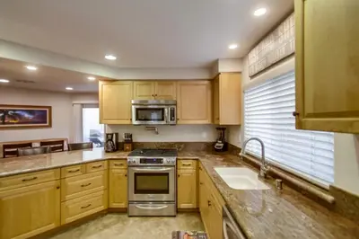 a kitchen with wooden cabinets and stainless steel appliances at Sail Bay Luxury Retreat With Private Spa and Rooftop Bay View in San Diego