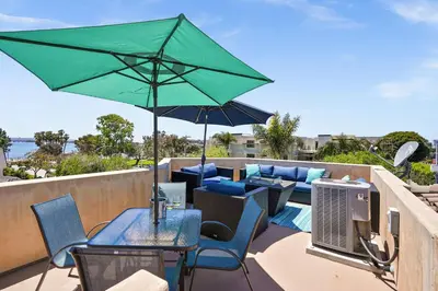 a table with a green umbrella on a balcony at Sail Bay Luxury Retreat With Private Spa and Rooftop Bay View in San Diego