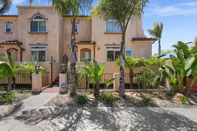 a house with palm trees in front of a fence at Sail Bay Luxury Retreat With Private Spa and Rooftop Bay View in San Diego