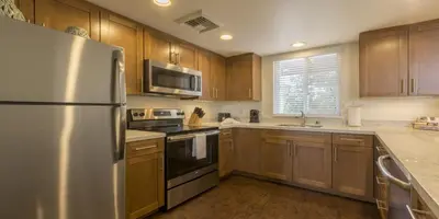 a kitchen with wooden cabinets and a stainless steel refrigerator at Grand Pacific Palisades in Carlsbad