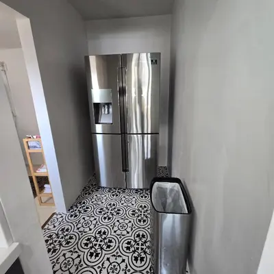 a kitchen with a stainless steel refrigerator on a tile floor at Wise in San Diego