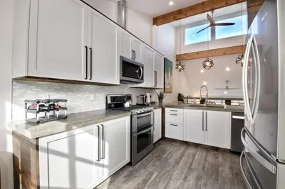 a kitchen with white cabinets and a stainless steel refrigerator at Sea Bluff - Direct Beach Access in Encinitas