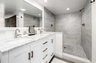 a white bathroom with two sinks and a shower at Sea Bluff - Direct Beach Access in Encinitas