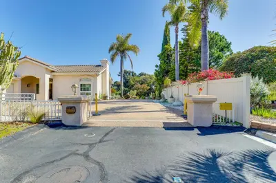 a house with a fence and palm trees at 3 Mi to Beach Central and Elegant Home in Oceanside in Oceanside