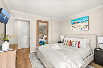 a white bedroom with a large bed and a television at Seize the Day in San Diego
