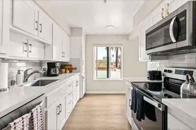 a white kitchen with white cabinets and a sink at Seize the Day in San Diego
