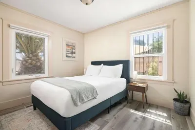a bedroom with a large bed with two windows at Cozy Ocean Beach Bungalow in San Diego