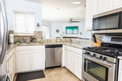 a kitchen with white cabinets and stainless steel appliances at Balboa Escape An Iconic Stay in Newport Beach