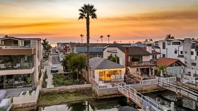 a city with houses and a palm tree at sunset at Bayside Getaway Waterfront in Newport Beach