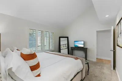 a white bedroom with a bed and a television at SoCal's Finest Gem on Dahlia in Corona del Mar