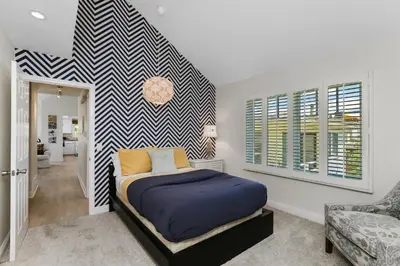 a bedroom with a bed and a striped wall at SoCal's Finest Gem on Dahlia in Corona del Mar