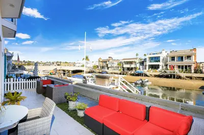 a balcony with a red couch and a marina at Grand Canal Getaway - Balboa Island in Newport Beach