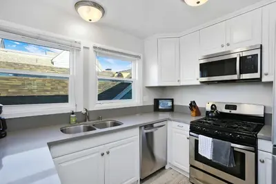 a kitchen with white cabinets and a sink and a stove at Grand Canal Getaway - Balboa Island in Newport Beach