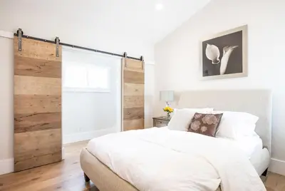 a bedroom with a white bed and a sliding barn door at A True Vacation Masterpiece in Corona del Mar