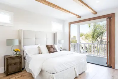 a white bedroom with a bed and a large window at A True Vacation Masterpiece in Corona del Mar