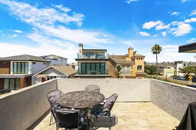 a table and chairs on the balcony of a house at Newport Retreat B - Walk to Sandy Beaches in Newport Beach