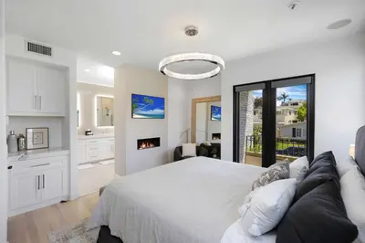 a white bedroom with a bed and a kitchen at Poinsettia Palms - Chic & Luxe Patio Near Beach in Corona del Mar