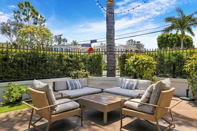 a patio with a couch and two chairs and a table at Poinsettia Palms - Chic & Luxe Patio Near Beach in Corona del Mar
