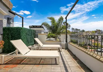 a balcony with two white chairs on a roof at Poinsettia Palms - Chic & Luxe Patio Near Beach in Corona del Mar