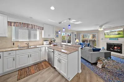 a kitchen with white cabinets and a living room with a couch at Ruby Villa B - Upper Unit for 6 in Newport Beach