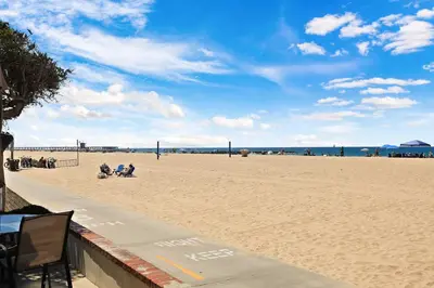 a beach with people sitting on the sand at Seashore Sun and Fun - On Beach in Newport Beach
