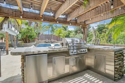 an outdoor kitchen with a grill and a patio at Serene hillside oasis with pool - 20 min to beach in Oceanside