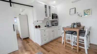 a kitchen with white cabinets and a table and a refrigerator at Rise Suites Oceanside in Oceanside