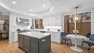 a kitchen with white cabinets and a table with chairs at Backyard Oasis w Fire Table Walk to Salt Creek Beach Dana Point Dreams in Dana Point