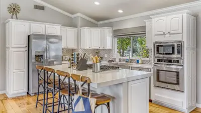 a kitchen with white cabinets and a stainless steel refrigerator at Temecula Wine Country Home w Pool Hot Tub Game Room Vineyard Views in Country Road Estates