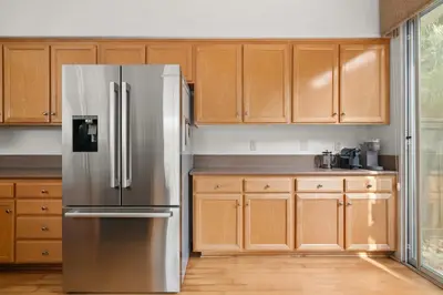 a kitchen with wooden cabinets and a stainless steel refrigerator at Sweet Serenity 3 bed with community pool, spa in Encinitas
