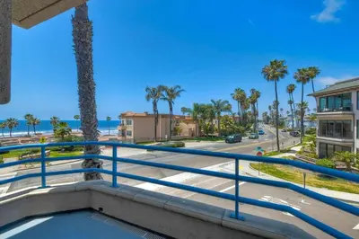 a balcony with a view of the beach and palm trees at Nomad's Oceanfront Retreat 2B2B Condo in Oceanside