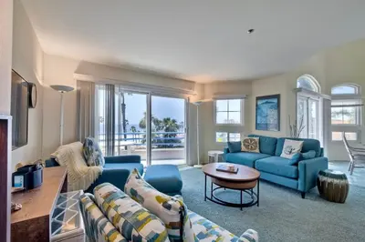 a living room with blue couches and a table at Nomad's Oceanfront Retreat 2B2B Condo in Oceanside