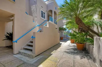 a house with stairs in front of a building with palm trees at Nomad's Oceanfront Retreat 2B2B Condo in Oceanside