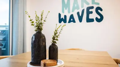 two black vases with plants in them on a table at Steps from the SandBoardwalk Outdoor Dining Parking and Patio in Newport in Newport Beach