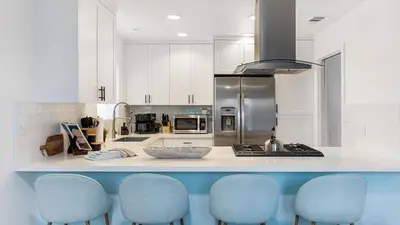 a kitchen with a counter with four blue chairs at Steps from the SandBoardwalk Outdoor Dining Parking and Patio in Newport in Newport Beach