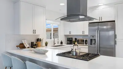 a kitchen with white cabinets and a stainless steel refrigerator at Steps from the SandBoardwalk Outdoor Dining Parking and Patio in Newport in Newport Beach